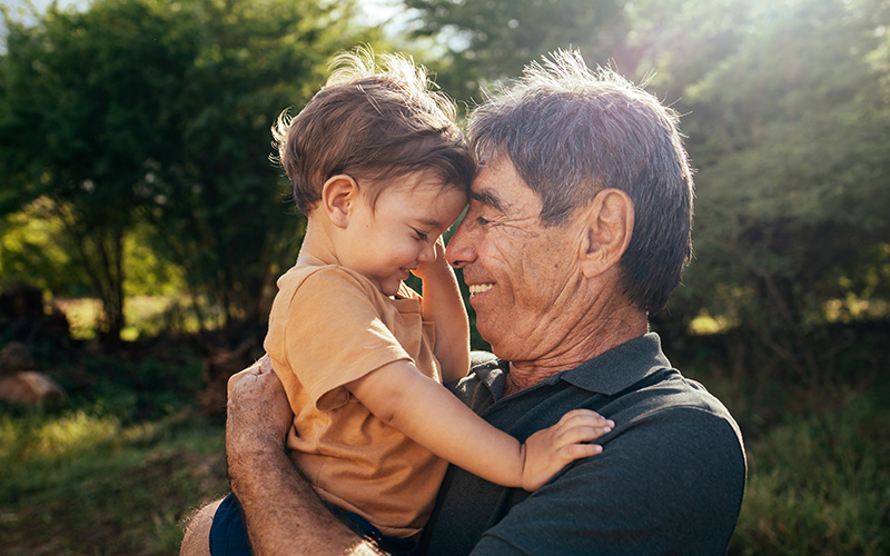 An older man embraces his grandson with a smile on his face