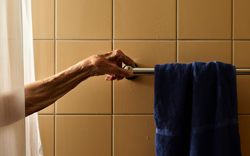 An elderly woman reaches for a towel as she attempts to get out of the shower